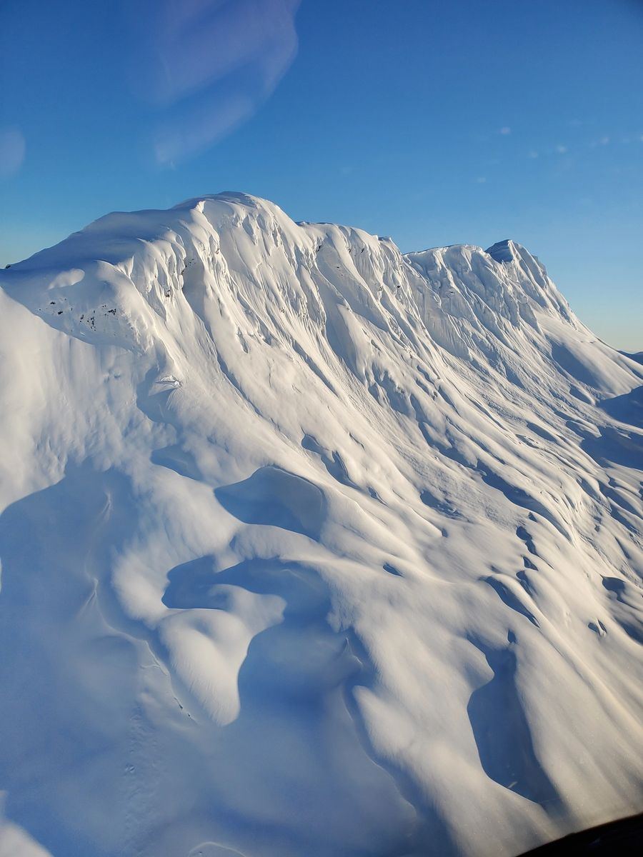 SMG helicopter flying above Alaska peaks with a veteran Girdwood pilot